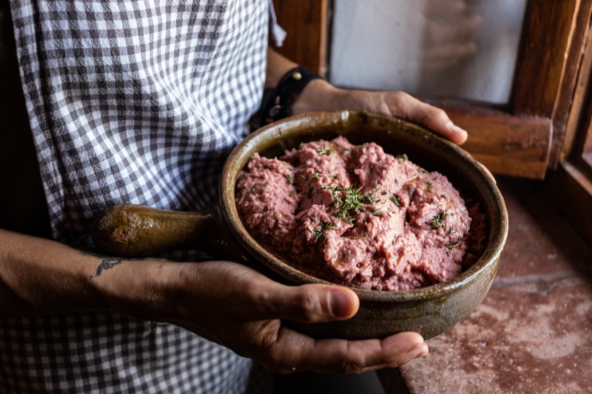 Person holding a rustic bowl with plant-based food
